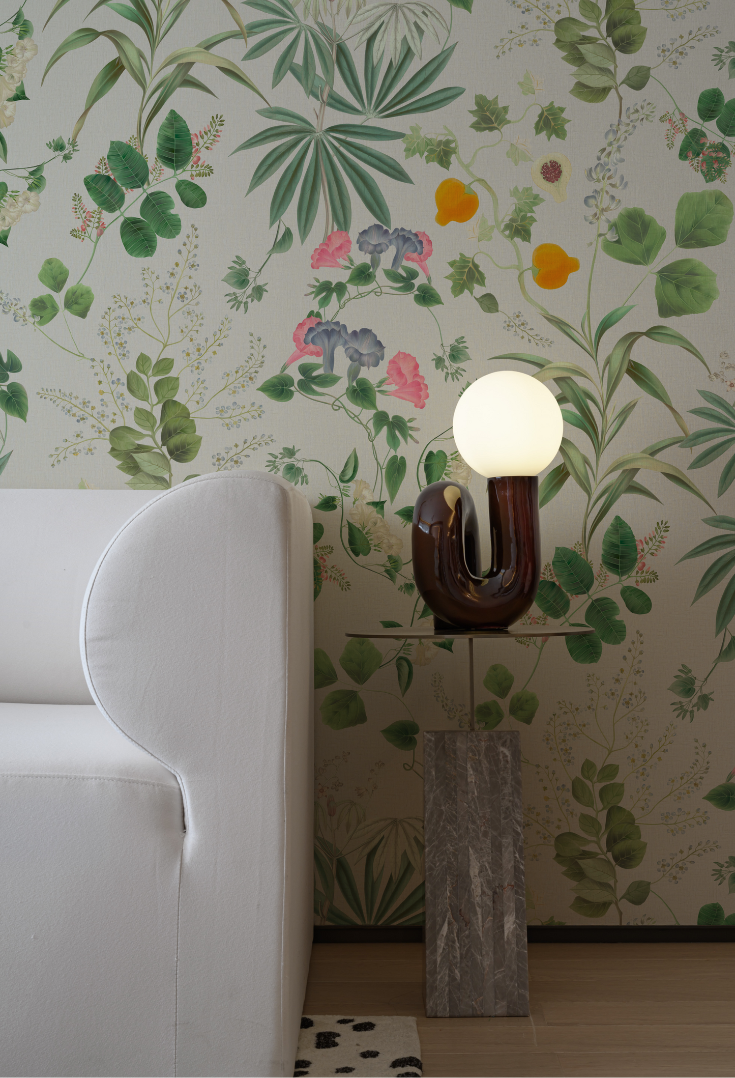 A sofa and modern Lamp with Luxury botanical Eden Wallpaper in White Meadow from Deus ex Gardenia.