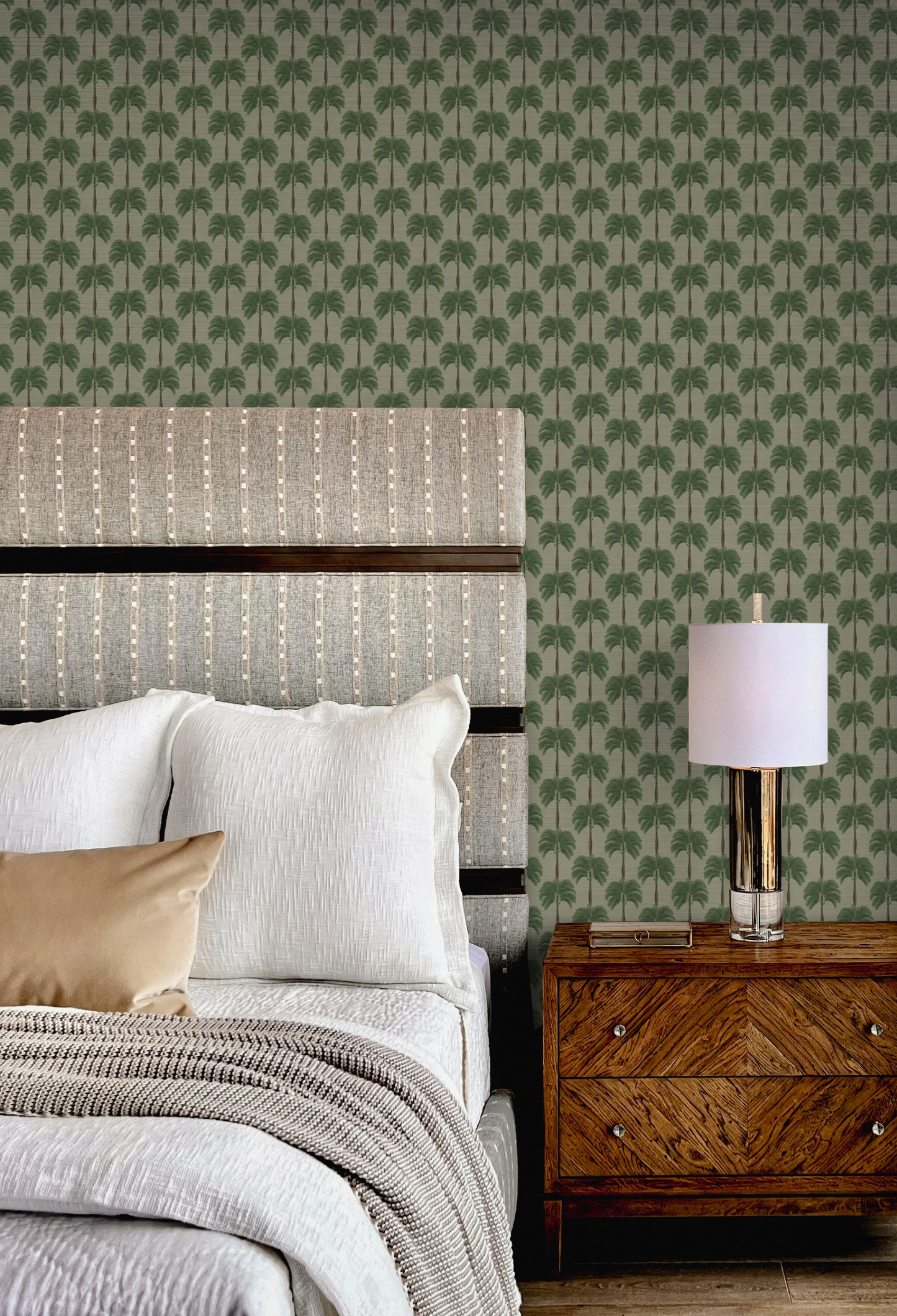 A luxury bedroom with a bed and lamp on side table with a background of small palm tree wallpaper of Little Palma in Sand by Deus ex Gardenia.