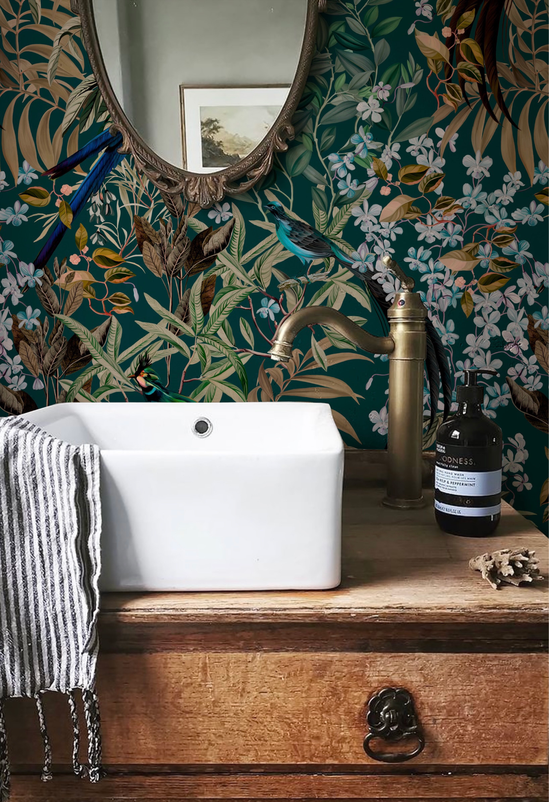 Luxury vintage inspired bathroom with sick on wooden cabinet and mirror surrounded by Deus ex Gardenia's Resplendent Woods Wallpaper in Forest of tropical birds, blue flowers and palms. Photo by Park Place Gower.